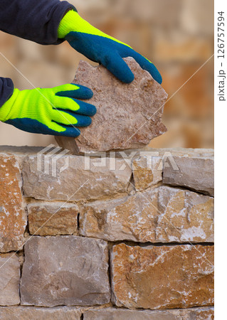 Mason hands working on masonry stone wall Mason hands working on masonry stone wall 126757594
