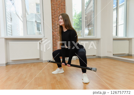 Young woman squatting with fitness bar in gym studio. Young woman squatting with fitness bar in gym studio. 126757772