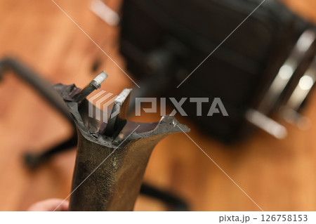 Man holding broken leg of office chair: workplace trouble, defective chair Man holding broken leg of office chair: workplace trouble, defective chair 126758153