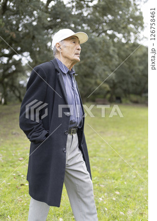 Senior professor walking and listening to music in university campus park Senior professor walking and listening to music in university campus park 126758461