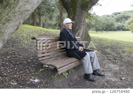 Senior man relaxing on park bench contemplating nature 126758480