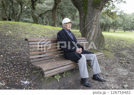 Senior man relaxing on park bench in autumn Senior man relaxing on park bench in autumn 126758482