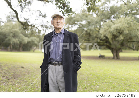 Elderly asian man wearing a hat and coat in a park Elderly asian man wearing a hat and coat in a park 126758498