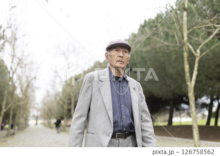 Elderly man listening music walking in park during winter 126758562