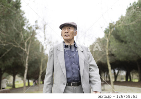 Elegant senior man listening music while walking in park 126758563