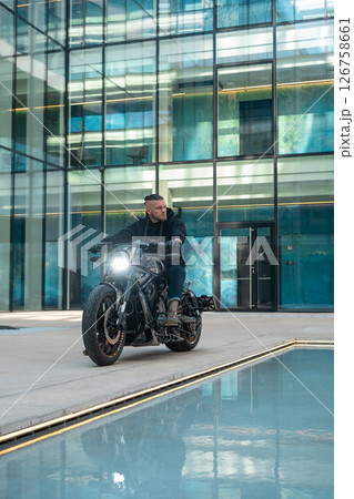 Handsome motorcyclist biker without helmet sitting on his moto against urban background. High quality photo Handsome motorcyclist biker without helmet sitting on his moto against urban background. High quality photo 126758661