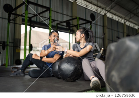 Friendship and Fitness. Friends enjoying a water break after a workout in a gym. Friendship and Fitness. Friends enjoying a water break after a workout in a gym. 126759630