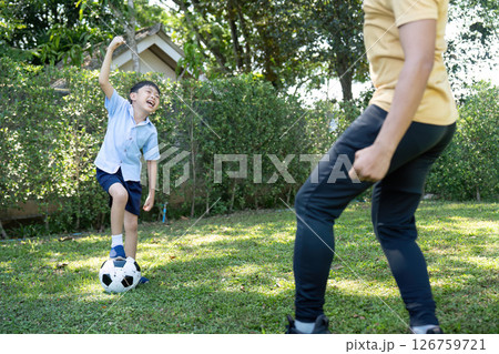 Activity: Young Boy Having Fun Kicking a Soccer Ball with Dad Activity: Young Boy Having Fun Kicking a Soccer Ball with Dad 126759721