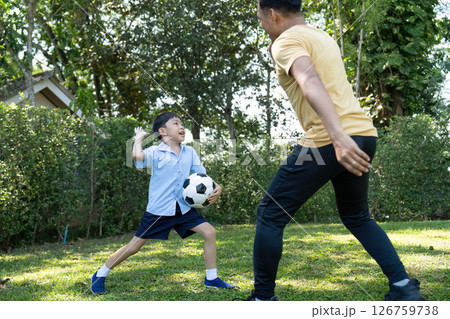 Activity: Father and son playing soccer in the garden, enjoying quality time together. Activity: Father and son playing soccer in the garden, enjoying quality time together. 126759738