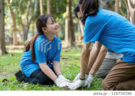 Family volunteers planting trees together in a green park for a better environment 126759786