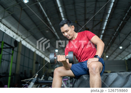 Wellness and Strength Training. Man lifting dumbbell in gym for fitness. 126759860