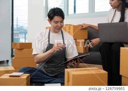 Couple analyzing logistics while managing packages in a shared workspace. Couple analyzing logistics while managing packages in a shared workspace. 126759901