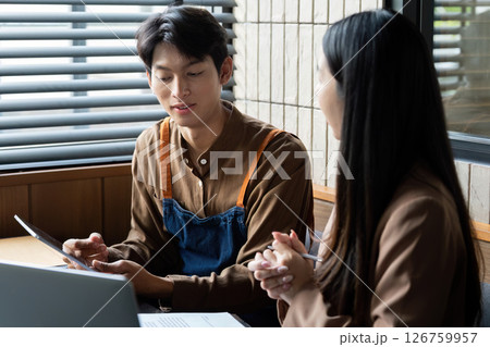 Collaboration and Communication. Young professionals discussing project details in a modern workspace. 126759957