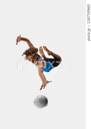 Sporty male athlete, volleyball player dives with focused look and open hand reaching for ball against white studio background. Concept of sport events Sporty male athlete, volleyball player dives with focused look and open hand reaching for ball against white studio background. Concept of sport events 126759960