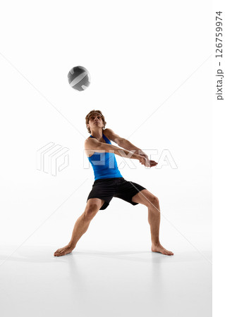 Volleyball athlete keeps eyes on ball and holds arms together in classic receive pose during game against white studio background. Player looks focused 126759974