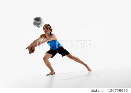 Volleyball athlete looks up with hands ready to receive ball during intense game moment against white studio background. 126759986