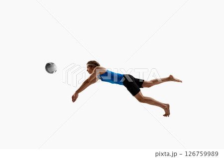 Dynamic photo of volleyball player stretches one arm in air while diving to reach ball showing quick reaction against white studio background 126759989