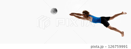 Banner. Male volleyball athlete in blue shirt jumps forward with arms stretched out aiming to block or save ball against white studio background. 126759991