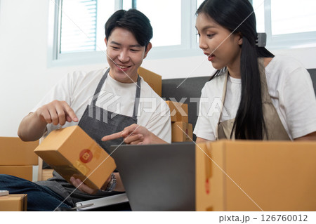 Couple Engaged in E-commerce Operations with Packages and Laptop Couple Engaged in E-commerce Operations with Packages and Laptop 126760012