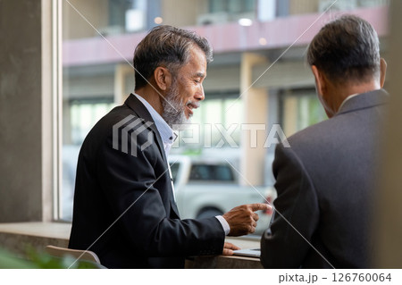 Elderly men discussing business strategies in a modern office setting 126760064