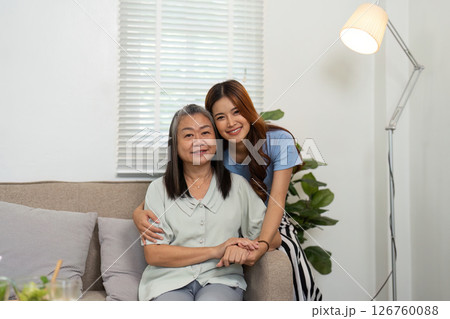 Wellness and Togetherness. Mother and daughter sharing a warm embrace on the couch. 126760088