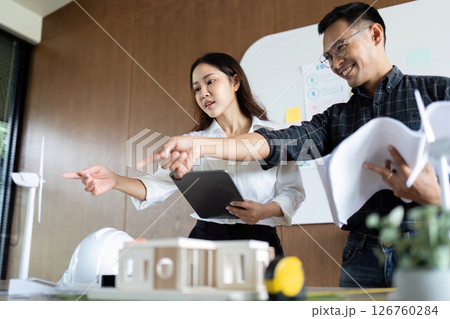 Sustainability and Engineering. Engineers pointing out features of eco-friendly designs in a collaborative setting. 126760284