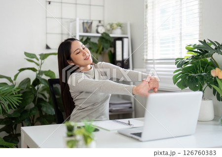 Workplace Wellness. Young woman enjoying a stretch break at her desk. Workplace Wellness. Young woman enjoying a stretch break at her desk. 126760383