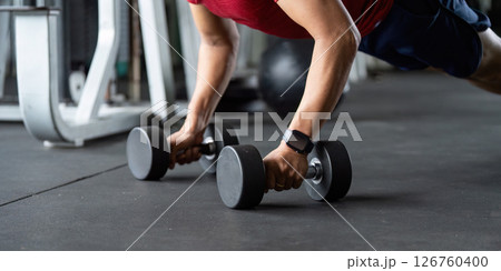 Wellness and Strength Training. Man performing push-up with dumbbells in gym. Wellness and Strength Training. Man performing push-up with dumbbells in gym. 126760400