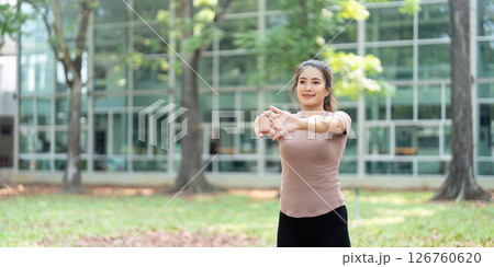 Wellness and Fitness. Young woman stretching her arms outdoors in a park. Wellness and Fitness. Young woman stretching her arms outdoors in a park. 126760620