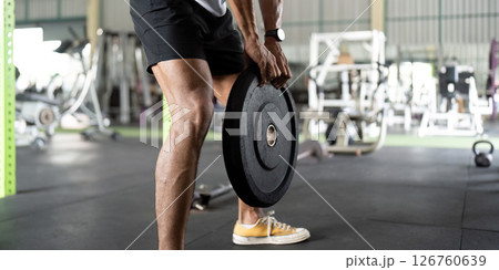Weightlifting: Young Man Lifting Heavy Plate in Gym 126760639
