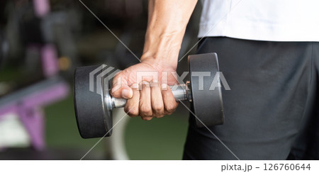 Strength Training. Close-up of man holding dumbbell in gym. 126760644