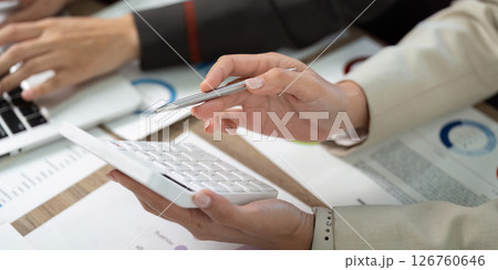 Team Collaboration and Financial Review. Colleagues discussing data with calculator and charts. 126760646