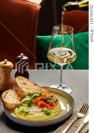 Waiter pouring white wine into glass with gourmet hummus, calamari, and bread Waiter pouring white wine into glass with gourmet hummus, calamari, and bread 126760782