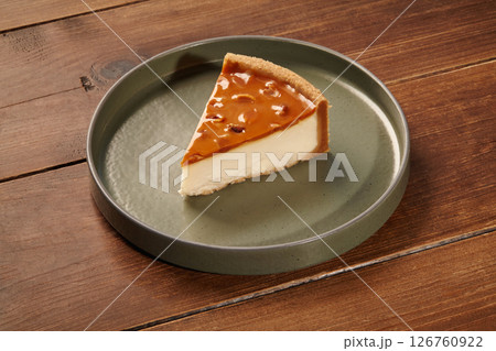 Slice of delicious caramel cheesecake resting on a green plate on a wooden table Slice of delicious caramel cheesecake resting on a green plate on a wooden table 126760922