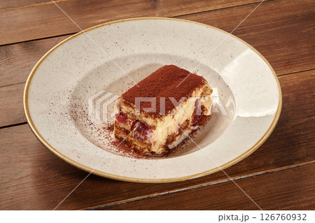 Delicious tiramisu cake with cocoa powder on elegant plate: indulging in sweet treat Delicious tiramisu cake with cocoa powder on elegant plate: indulging in sweet treat 126760932