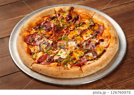Delicious pizza with salami, beef, cheddar, and chives resting on wooden table Delicious pizza with salami, beef, cheddar, and chives resting on wooden table 126760978