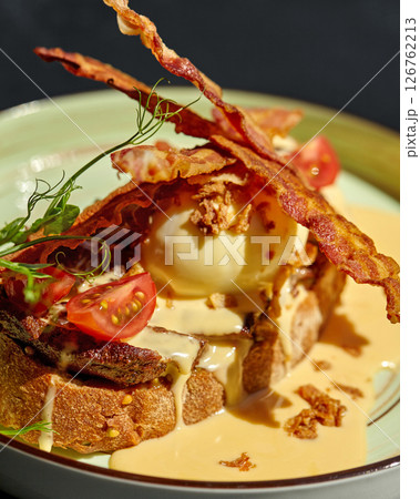 Gourmet breakfast or brunch with eggs benedict, bacon, hollandaise sauce, and cherry tomatoes on toasted bread Gourmet breakfast or brunch with eggs benedict, bacon, hollandaise sauce, and cherry tomatoes on toasted bread 126762213