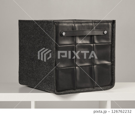 Elegant black leather and felt storage box with handle on white shelf 126762232