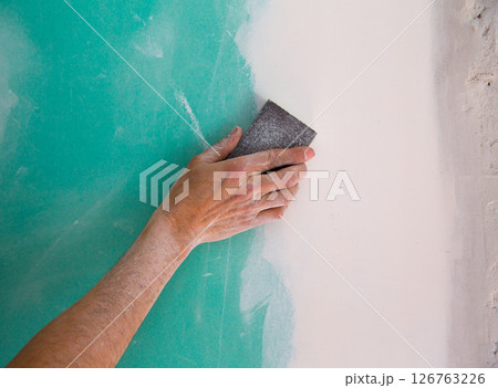 plastering man hand sanding the plaste in drywall seam plastering man hand sanding the plaste in drywall seam 126763226