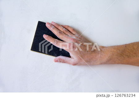 plastering man hand sanding the plaster 126763234