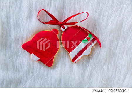 Christmas cookies red bell shape and ribbon on white fur Christmas cookies red bell shape and ribbon on white fur 126763304