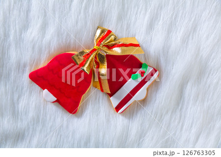 Christmas cookies red bell shape and ribbon on white fur Christmas cookies red bell shape and ribbon on white fur 126763305