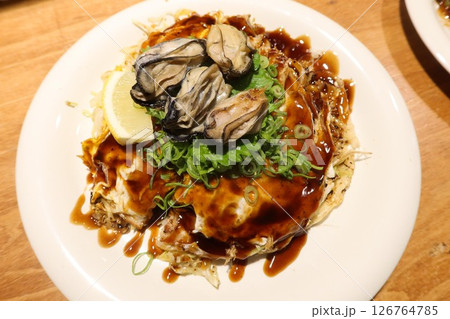 close up of Japanese pan fried Hiroshima Okonomiyaki with seafood and seaweed as toppings, udon noodles at the bottom of the omelette. close up of Japanese pan fried Hiroshima Okonomiyaki with seafood and seaweed as toppings, udon noodles at the bottom of the omelette. 126764785