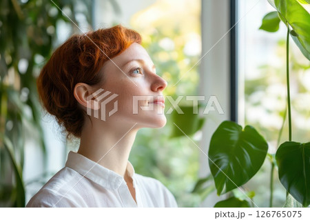 Young woman gazing thoughtfully out the window Young woman gazing thoughtfully out the window 126765075