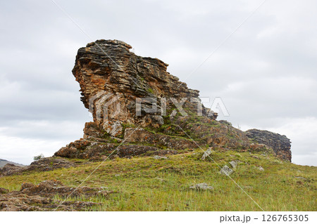 Unique rock formations rise above the grassy terrain. 126765305