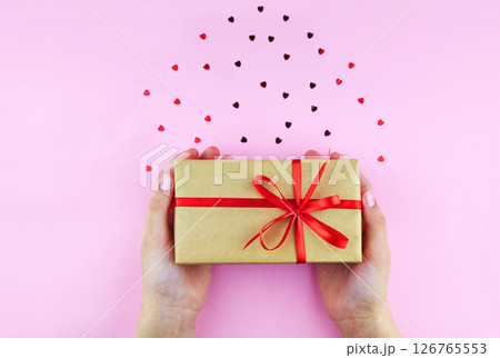 Women's hands hold a gift box. Valentines Day, Birthday. Ribbon heart Women's hands hold a gift box. Valentines Day, Birthday. Ribbon heart 126765553