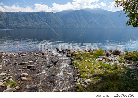 A tranquil lakeside setting featuring a flowing stream 126766850