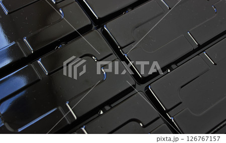 Niches and slots pressed into the black plastic surface Niches and slots pressed into the black plastic surface 126767157