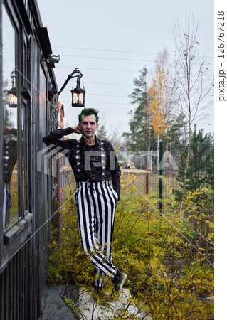 An Eccentric Clown Decked Out in Striped Attire Surrounded by Vibrant Autumn Foliage An Eccentric Clown Decked Out in Striped Attire Surrounded by Vibrant Autumn Foliage 126767218