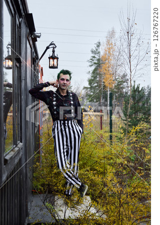 A Mysterious Clown in Striped Pants wanders through a beautiful Autumn Landscape 126767220